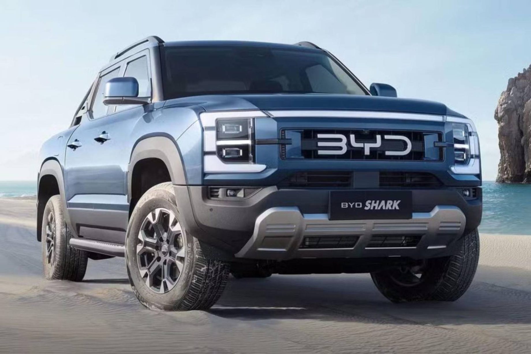 blue byd shark pickup truck parked on sandy beach