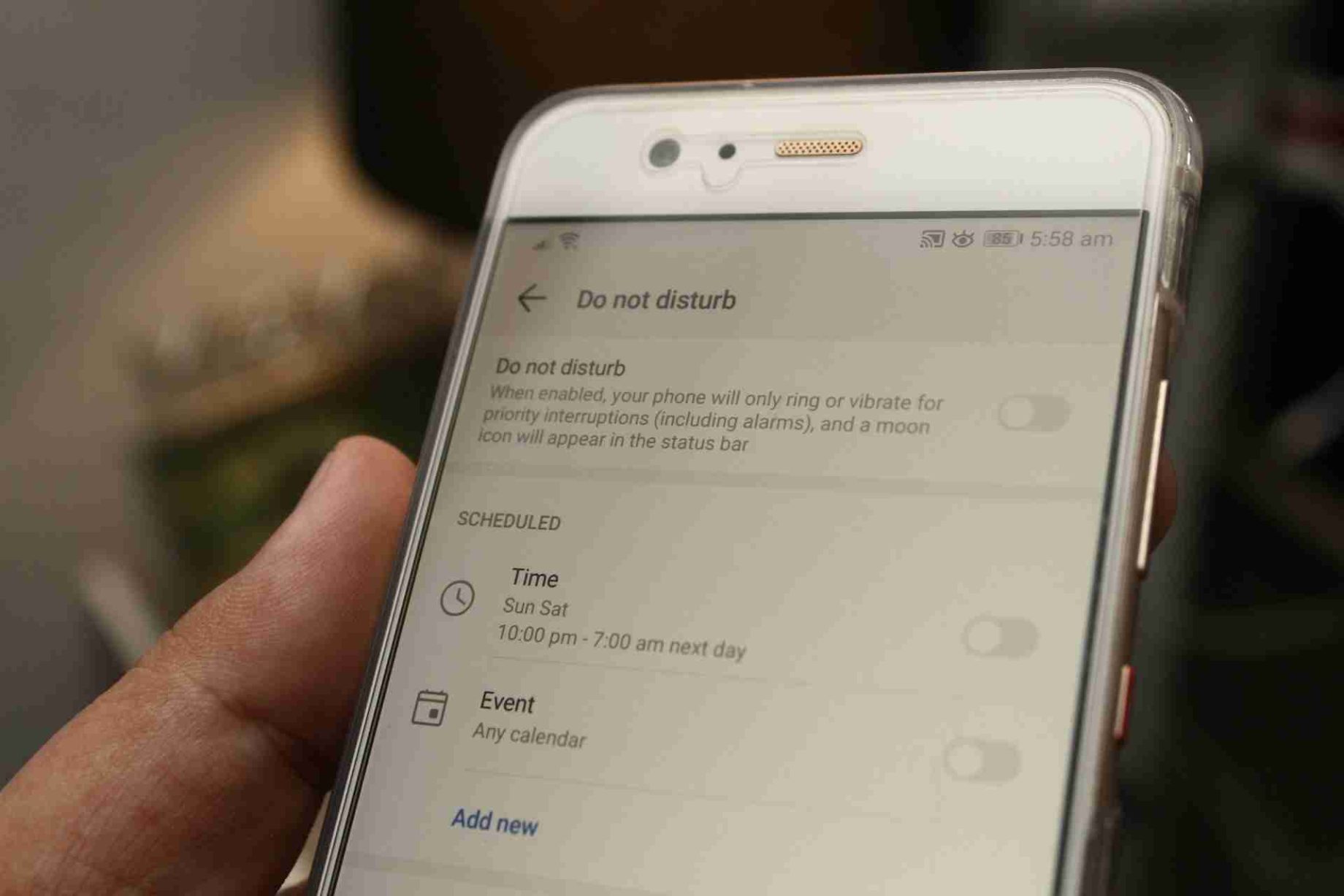 Person holding a smartphone displaying the Do Not Disturb settings screen