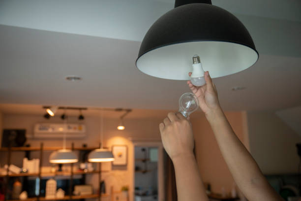 man changing compact fluorescent (cfl) bulbs with new led light bulb.