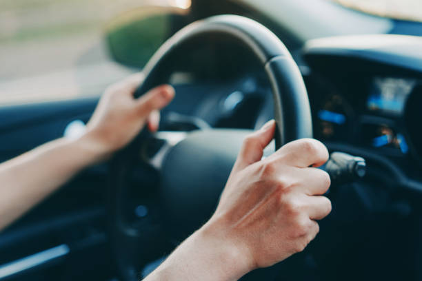 male hands holding steering wheel in a car