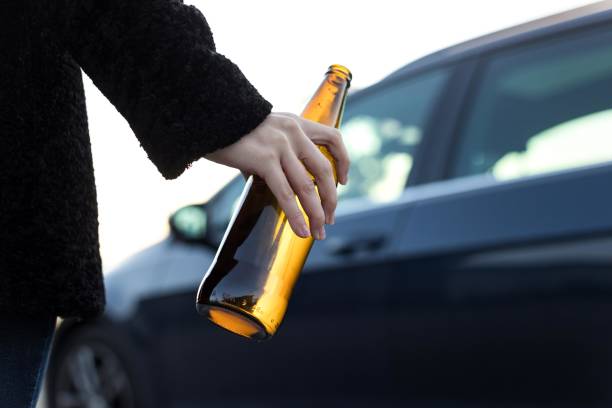 young adult drinking beer while driving, she is going to a party.