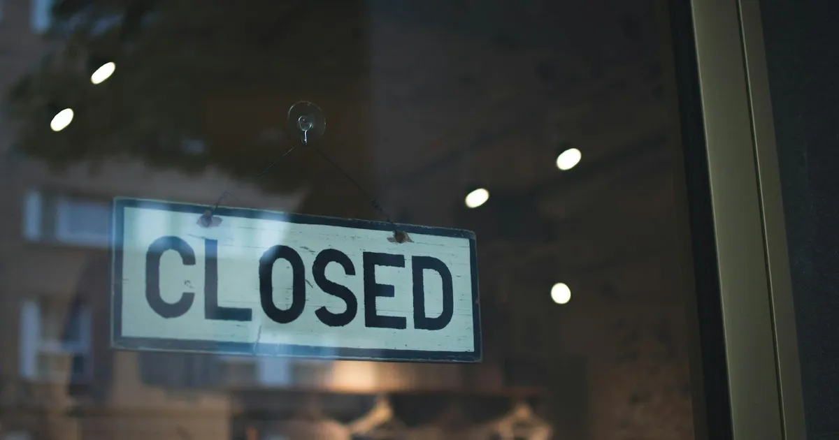 A closed sign hangs on a glass window of a modern urban storefront.