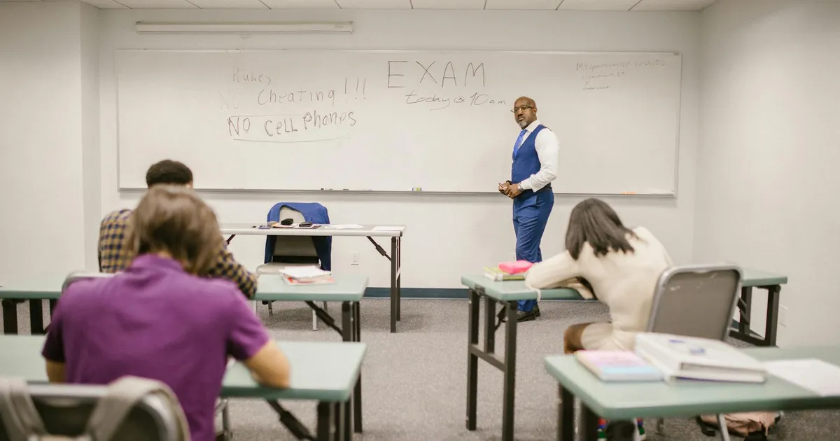 A college educator proctoring an exam, enforcing no cheating rules.