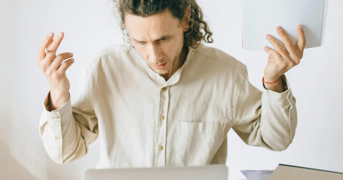 A frustrated man at his desk showing signs of exhaustion and stress in an office setting.