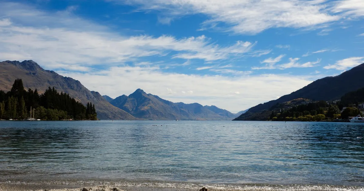 Tranquil views of Lake Wakatipu with surrounding mountains in Queenstown, New Zealand.