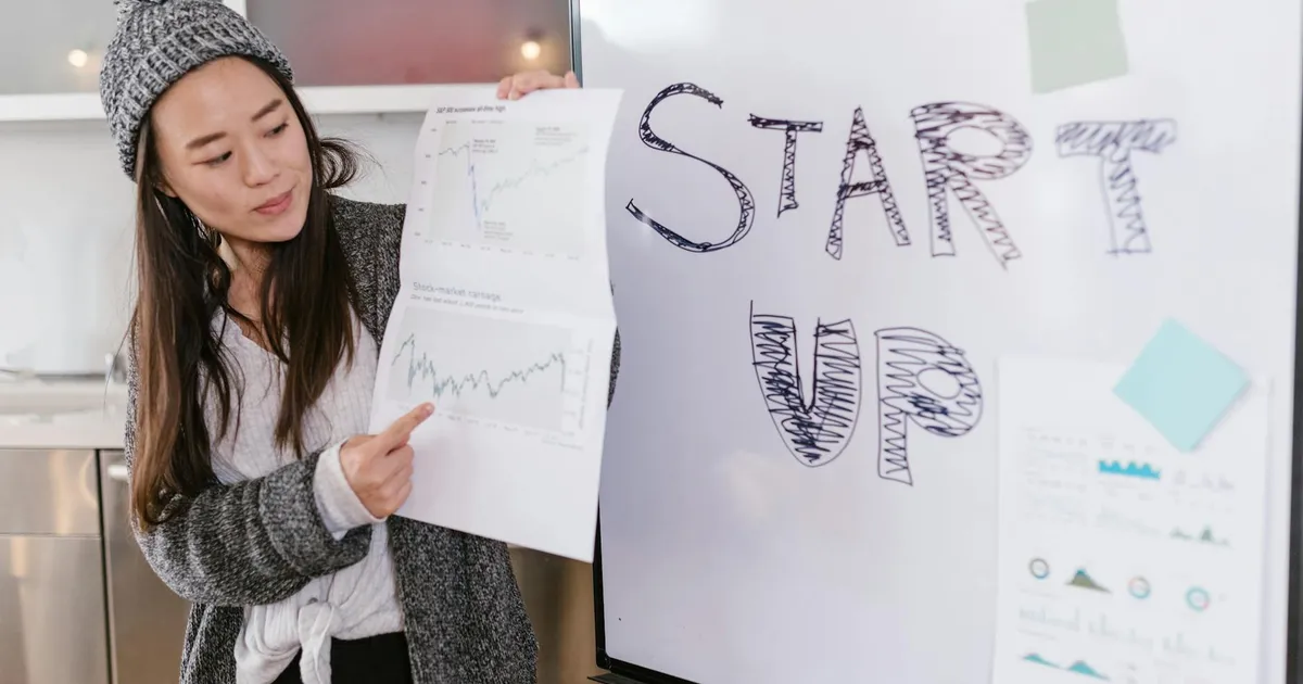 Asian woman presenting business growth charts during a startup pitch indoors.