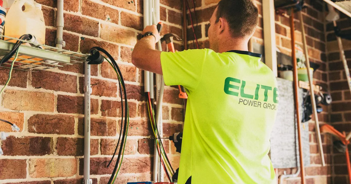Electrician performing solar battery installation for sustainable energy storage in a home setting.