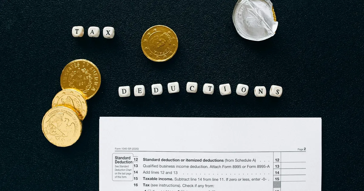 Image of tax deductions concept with coins and tax form on black background.