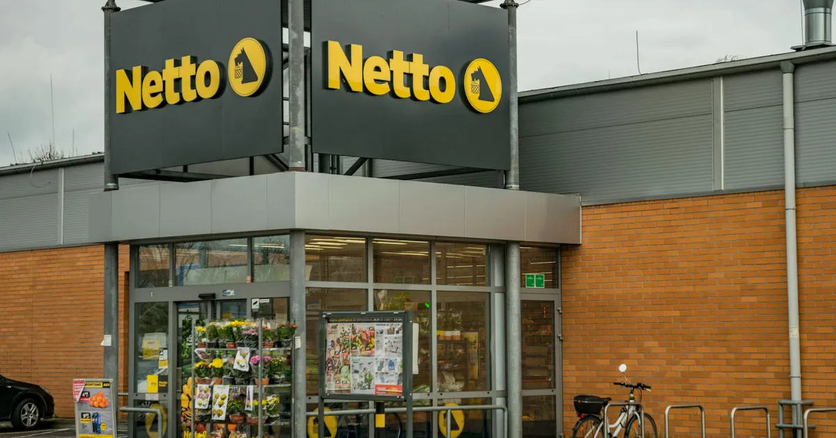 Exterior view of a Netto store with bicycles and a brick facade.