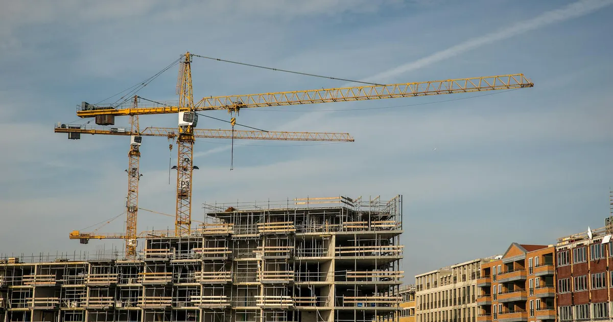 City construction site with cranes and partially built structures under a clear sky.