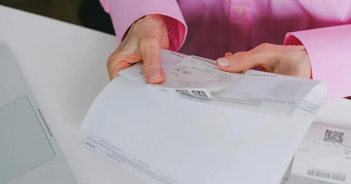Business person handling paper receipts, meticulously organized.