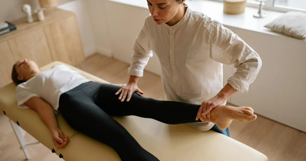 A physiotherapist assists a woman with leg rehabilitation therapy in a calm treatment room