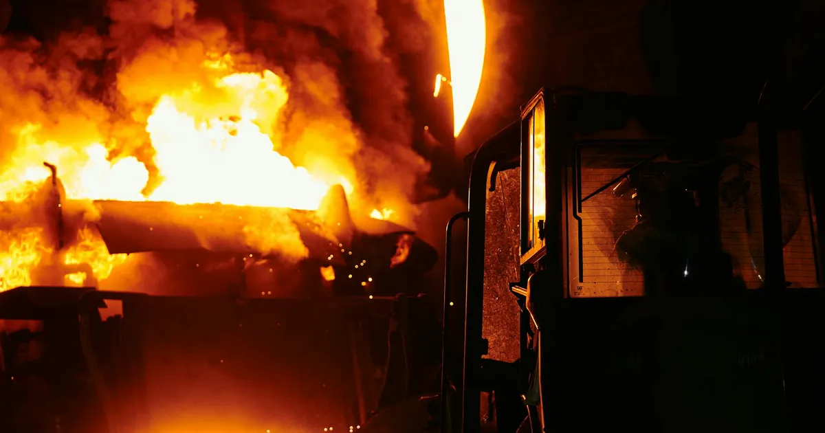 A dramatic scene of molten steel pouring in an industrial setting during nighttime.