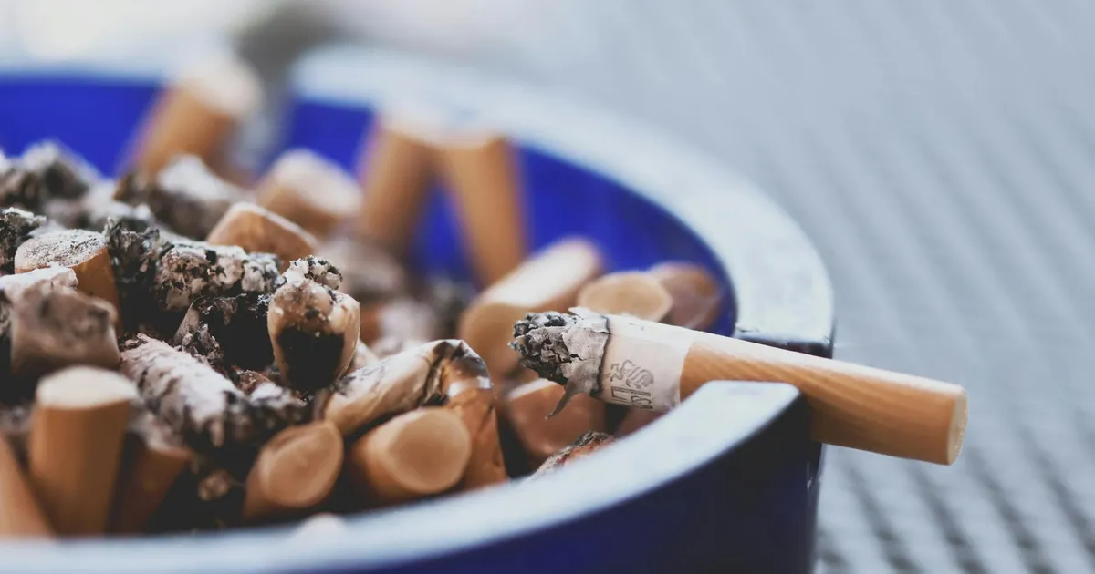 A close-up of cigarette butts in a blue ashtray, highlighting tobacco consumption.