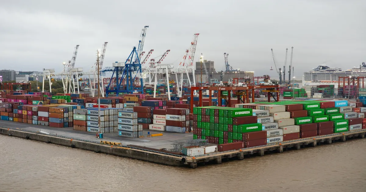 A bustling shipping port with stacked cargo containers and cranes under overcast skies.