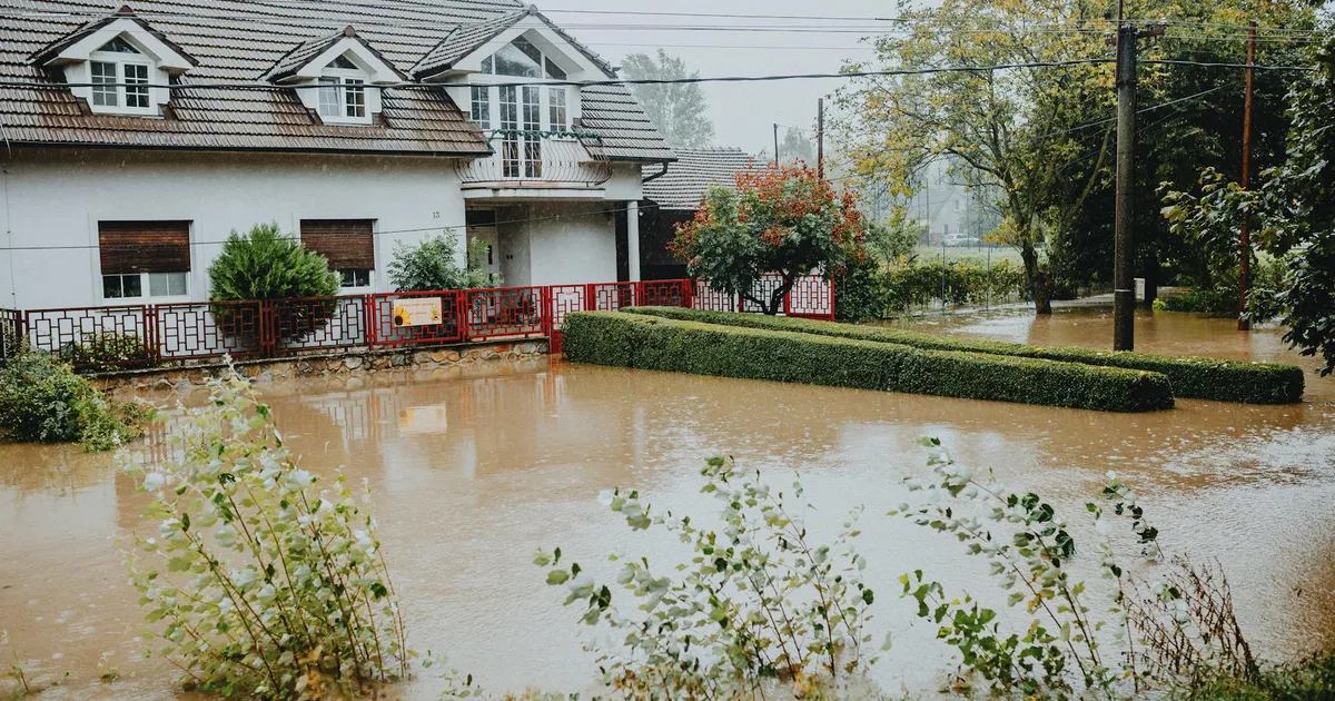 A suburban house surrounded by floodwaters after heavy rain, showing impact of natural disaster.