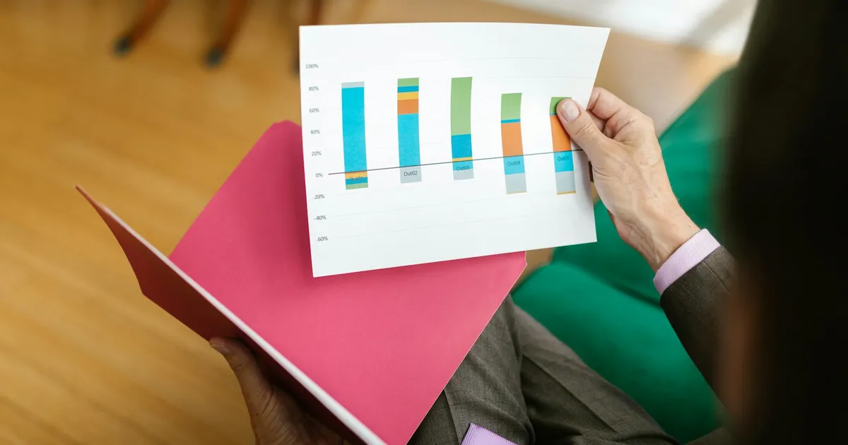 Close-up of a person analyzing a printed business report featuring a colorful bar graph.