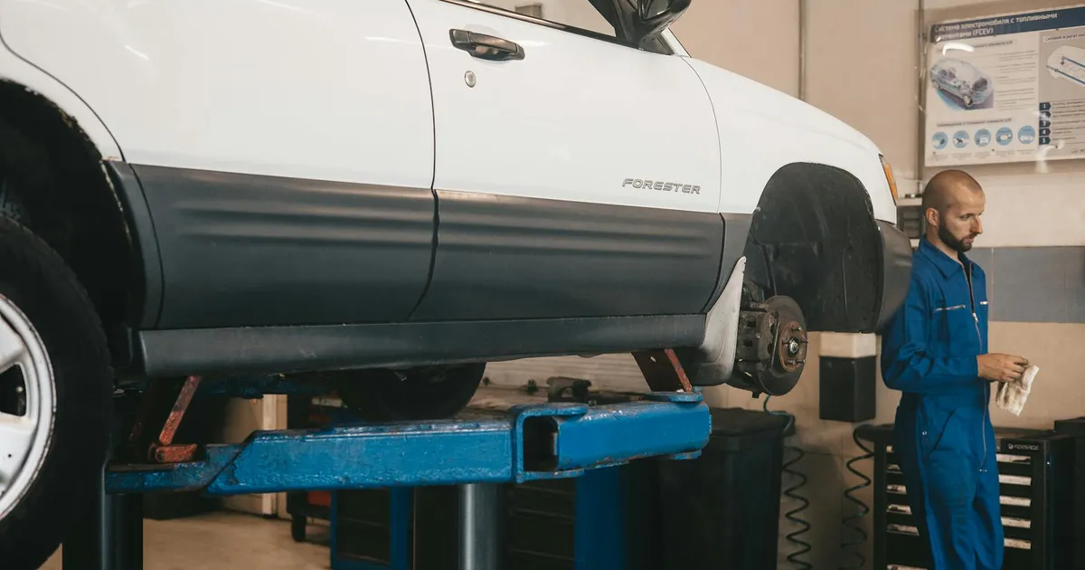 Mechanic evaluating a car on a lift for maintenance in an auto workshop.