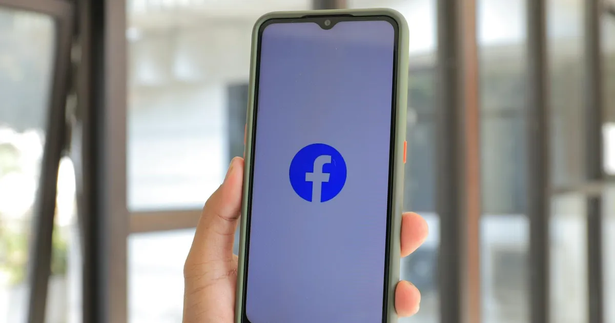 Close-up of smartphone with Facebook app open held by hand indoors.