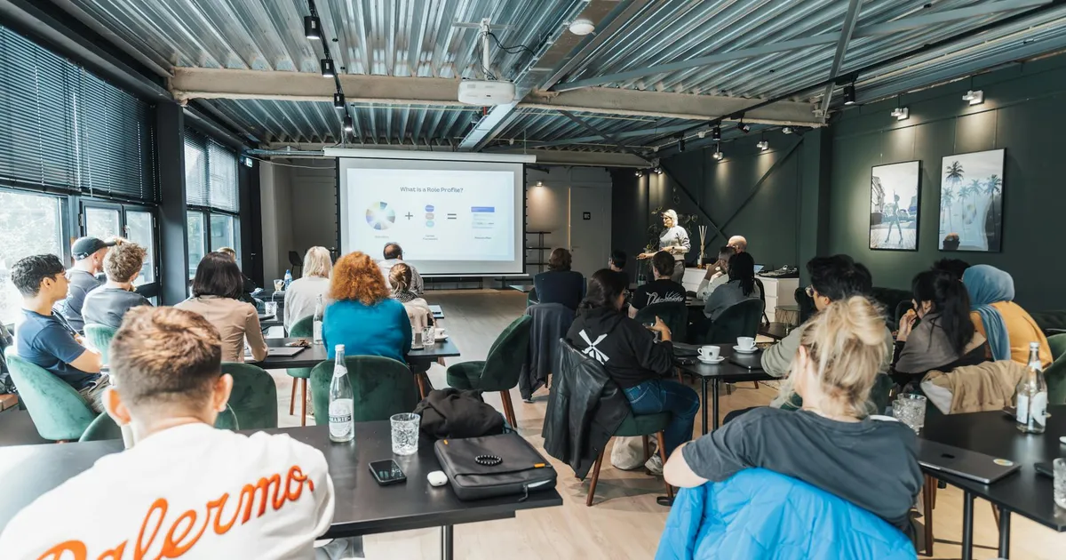 A diverse group attending an educational workshop indoors, focused on a presentation.