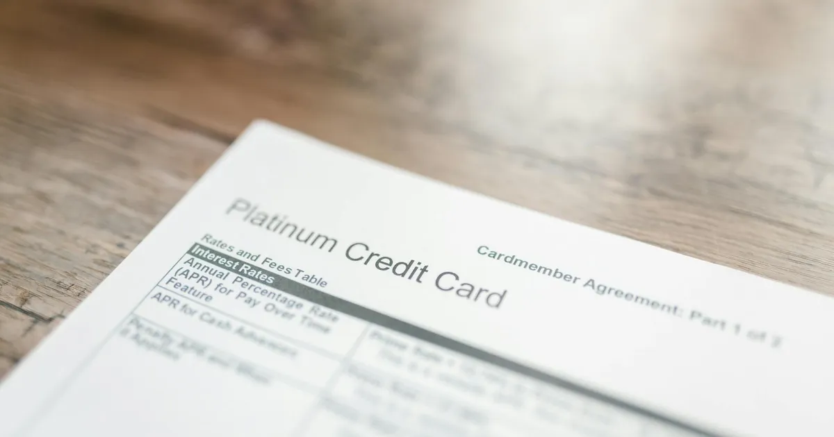 Close-up of a platinum credit card document with interest rates table on a wooden surface.