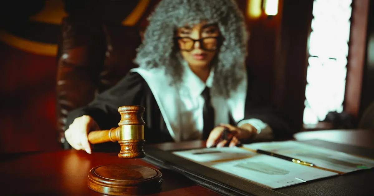 A judge in a courtroom holding a gavel, focused on legal documents.