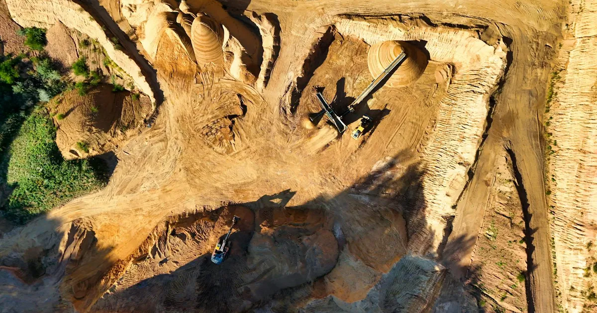 Stunning aerial photo showcasing a large open pit mining operation under sunny conditions.