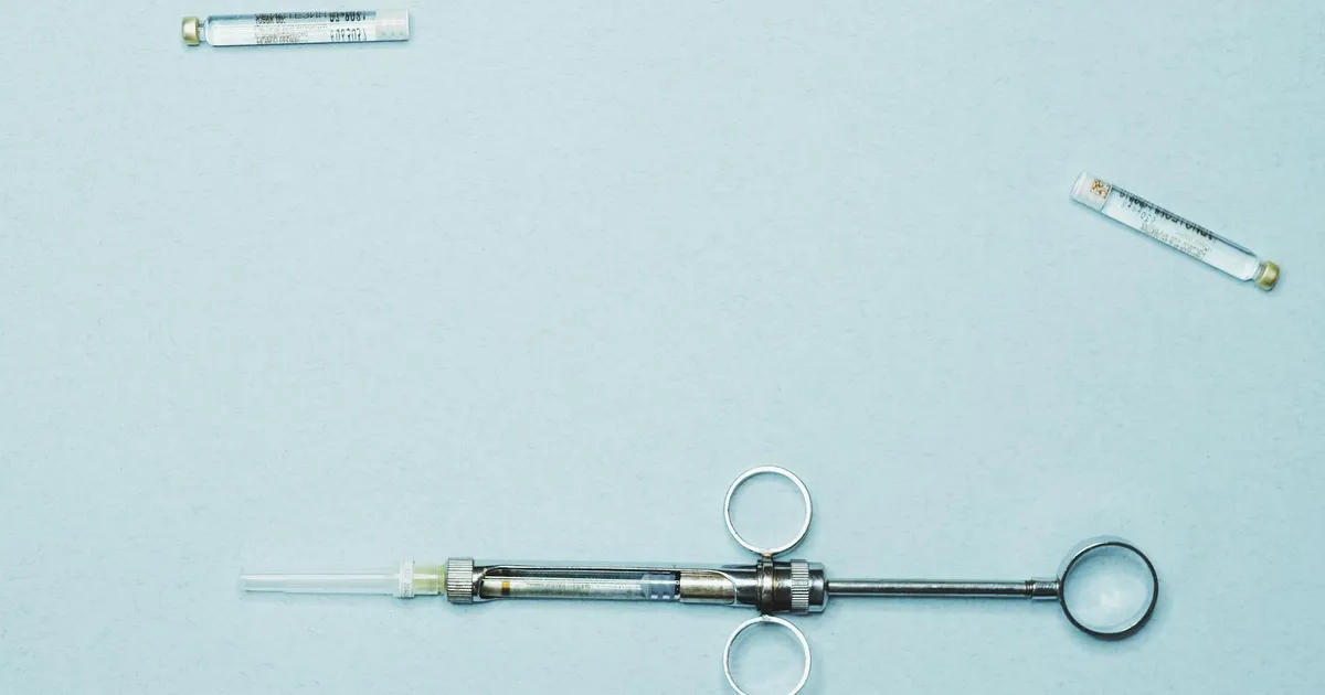 High-quality stock photo of a dental syringe and vials on a blue background. Ideal for dentistry.