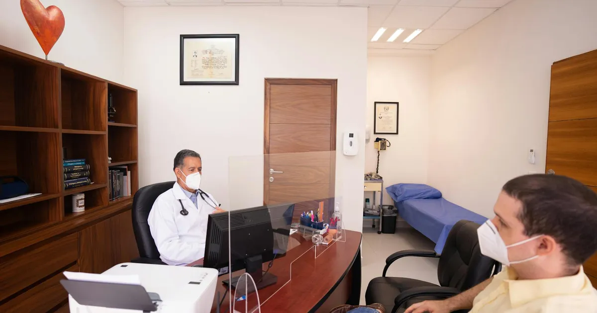 Doctor and patient with masks in medical clinic, emphasizing healthcare safety.