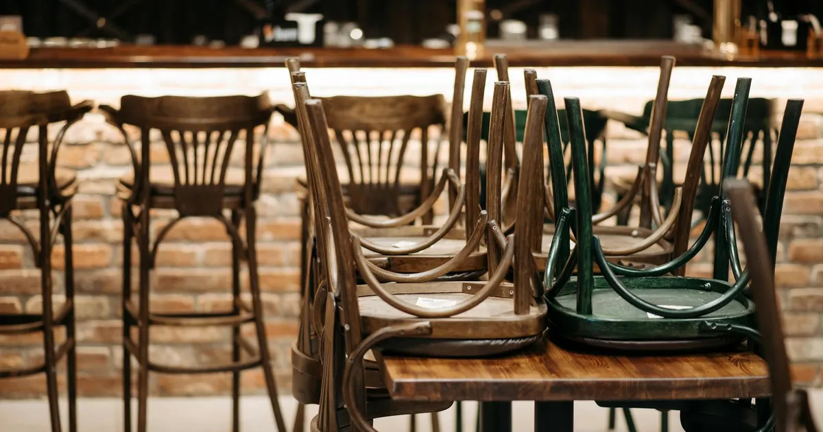 Stylish restaurant interior featuring stacked wooden chairs against a rustic, brick wall bar setting.