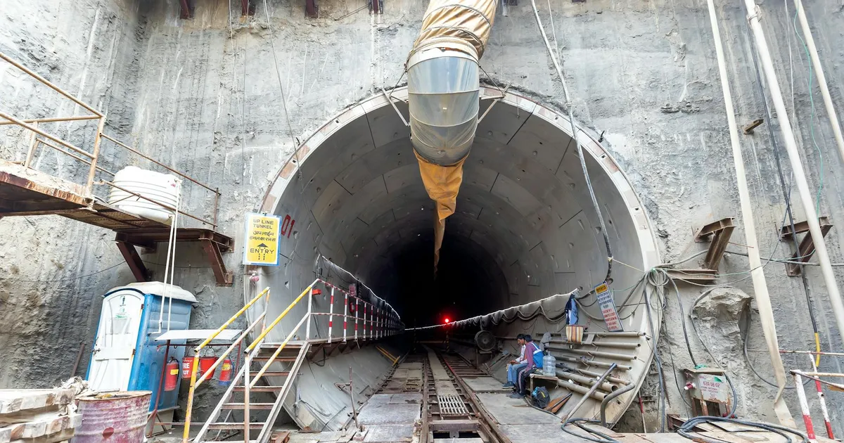 Industrial tunnel entrance under construction with heavy machinery and safety equipment.