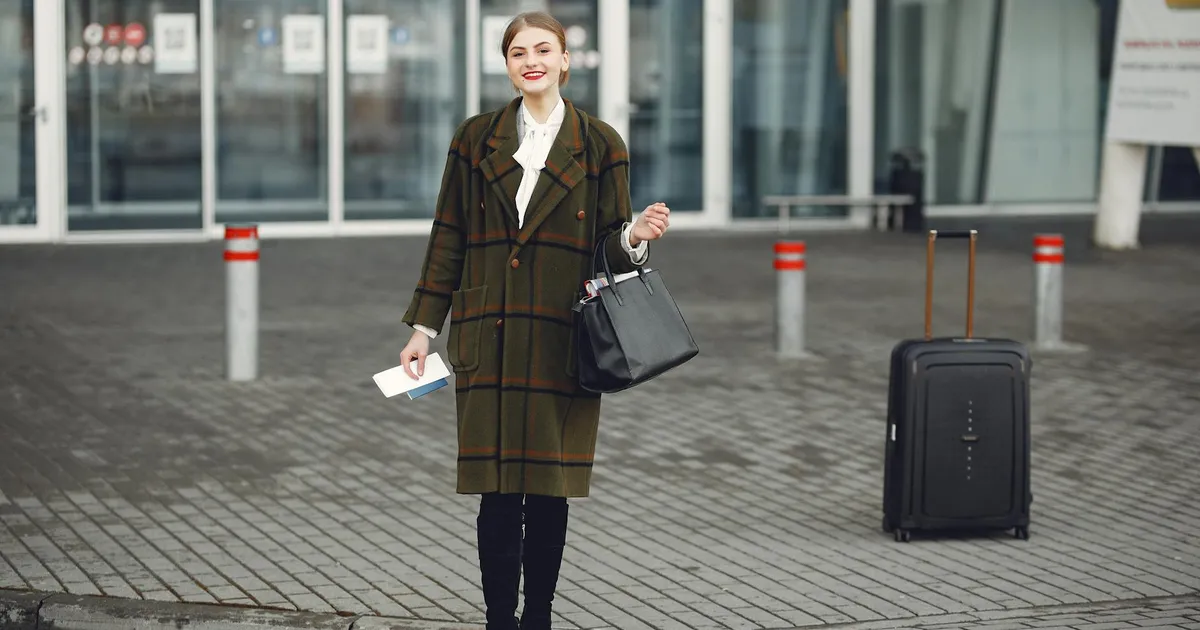 Fashionable woman with luggage arrives at airport ready for travel.