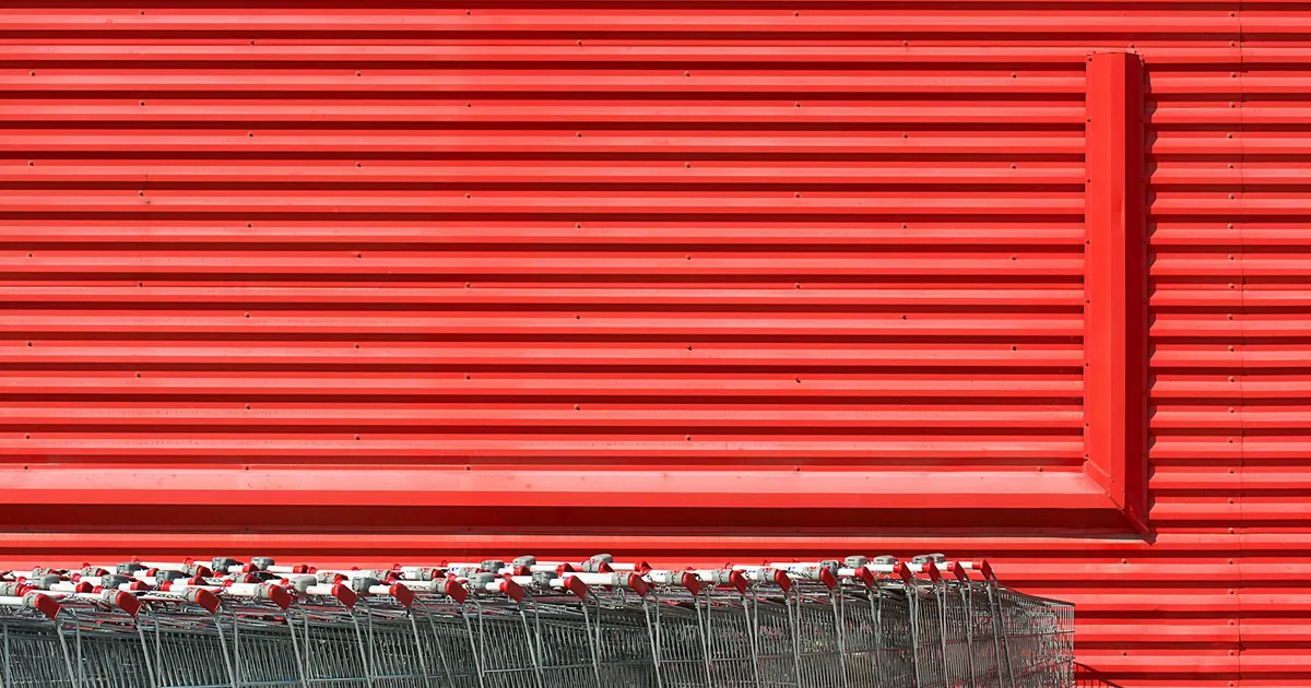 A vibrant red building facade with aligned metal shopping carts in front.