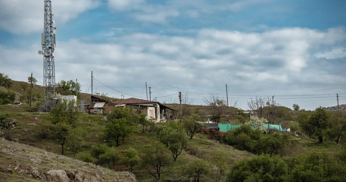 Scenic rural landscape with a cell tower and rustic houses in Elazığ, Türkiye.