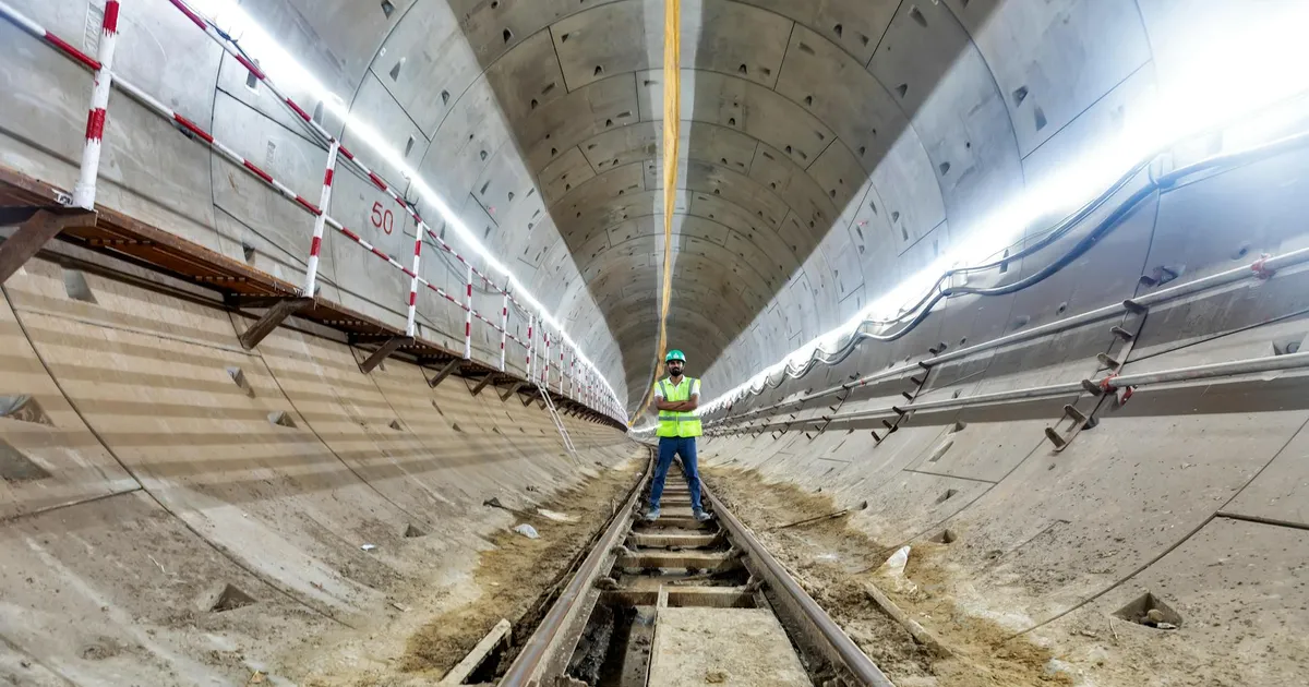 Engineer in safety gear inspects a subway tunnel under construction, highlighting urban development.
