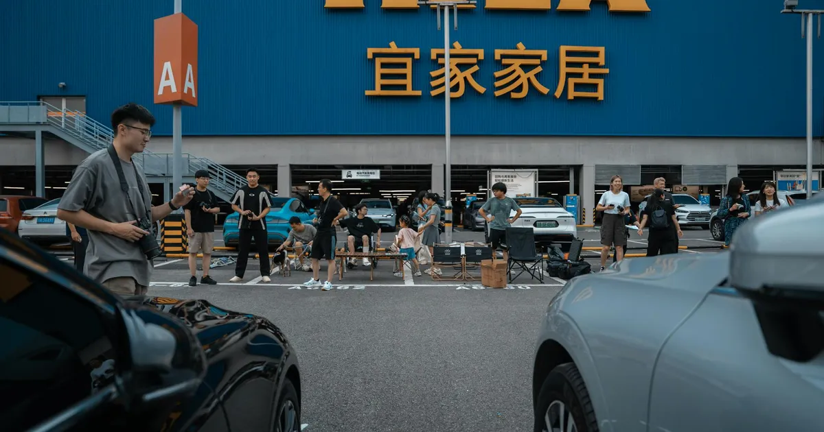 People enjoying a social gathering at an IKEA parking lot with cars and a large store sign.