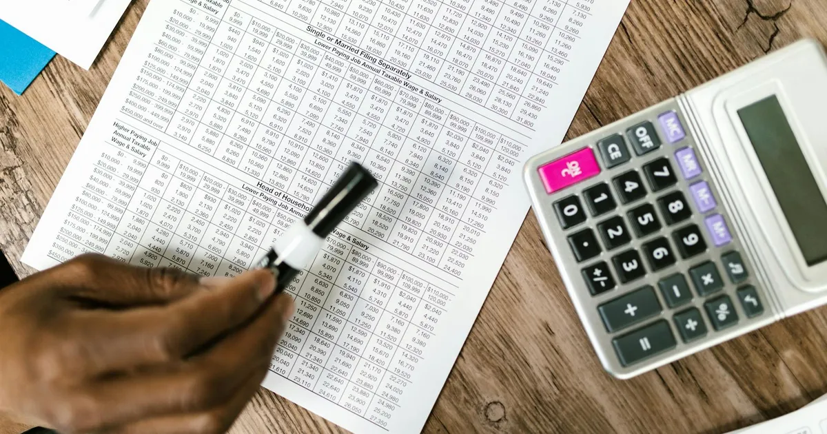 Close-up of tax documents and calculator on wooden table, highlighting financial analysis.