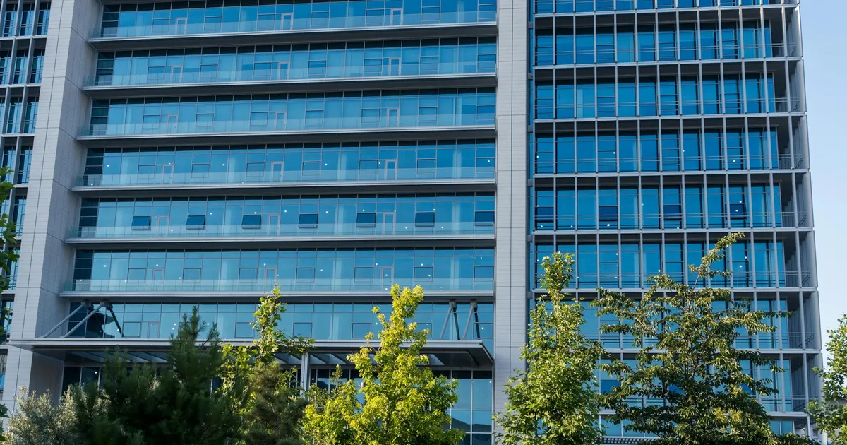 Glass facade skyscraper with trees in downtown urban scene, perfect for business and architecture themes.
