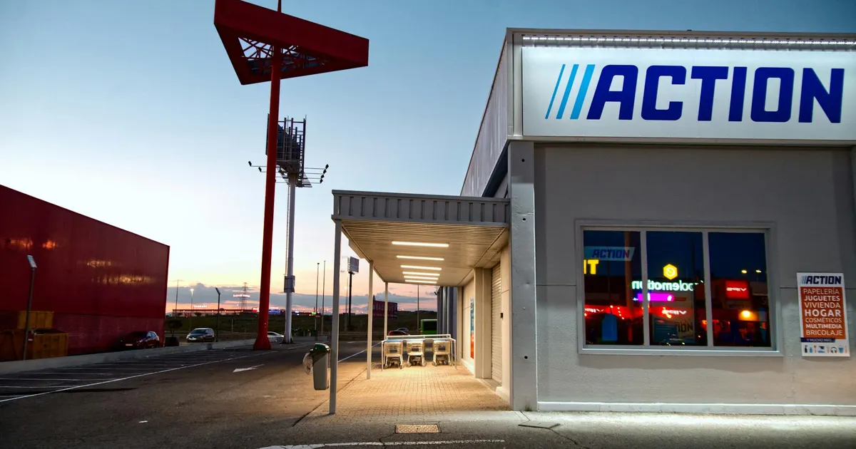 View of a commercial building with illuminated signage and empty parking during sunset.