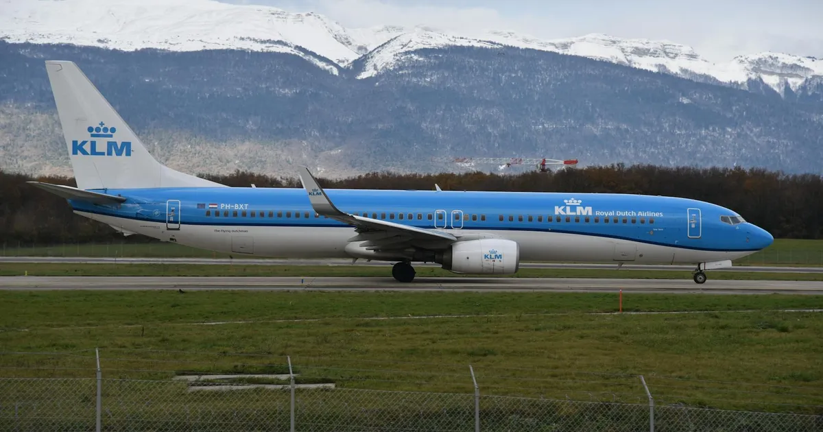 KLM Boeing 737 preparing for takeoff at Geneva Airport with snowy Jura Mountain backdrop.
