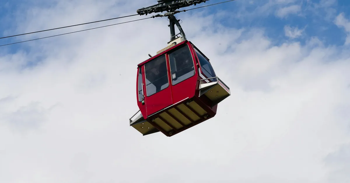 A red cable car suspended in the sky offers breathtaking views of the Swiss Alps.