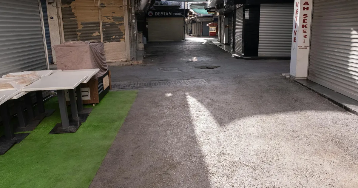 Deserted market street in İzmir with closed shops and roller doors.