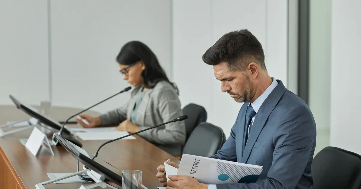 Business professionals in a conference setting, focusing on documents and reports.
