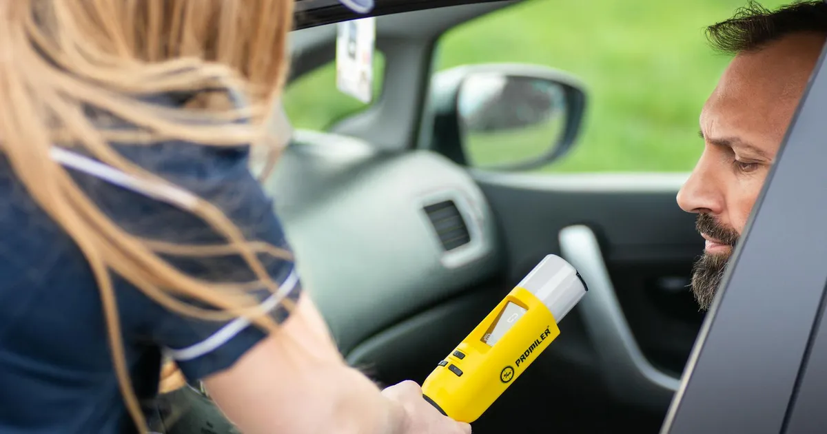 Police officer administering a breathalyzer test to a driver in a car, ensuring road safety.