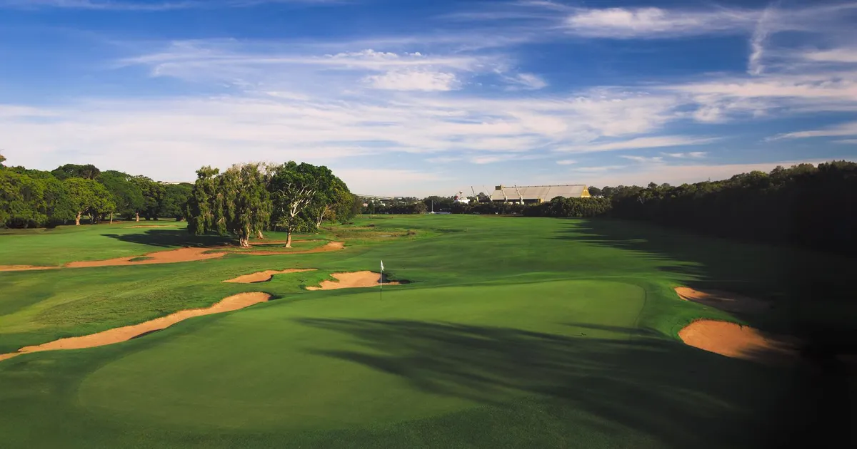 Aerial view of a lush green golf course under a blue sky, perfect for outdoor sports enthusiasts.