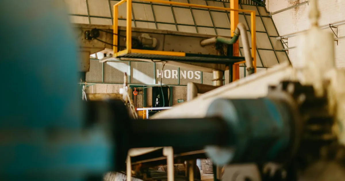 Close-up of heavy machinery inside an industrial factory with focus on ironworks and conveyor systems.