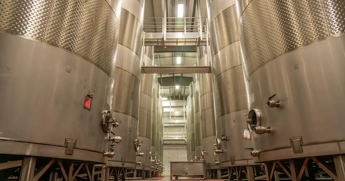 Interior of an industrial brewery with large, stainless steel fermentation tanks.