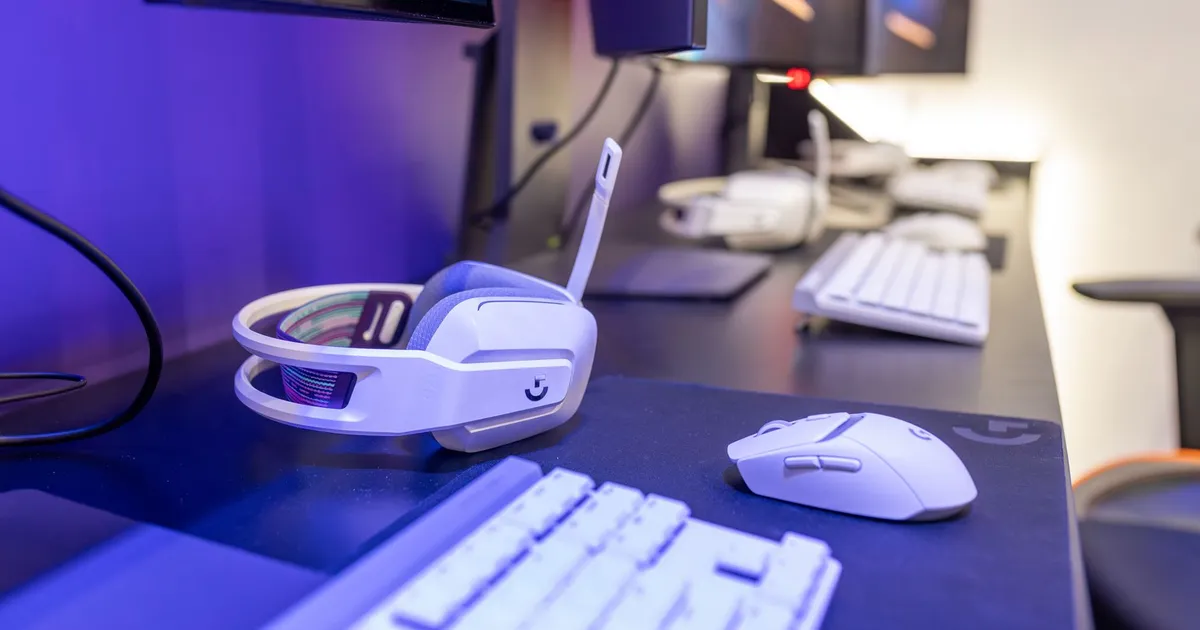 Close-up of a gaming setup featuring a white headset, computer mouse, and keyboard with a vivid lighting ambiance.