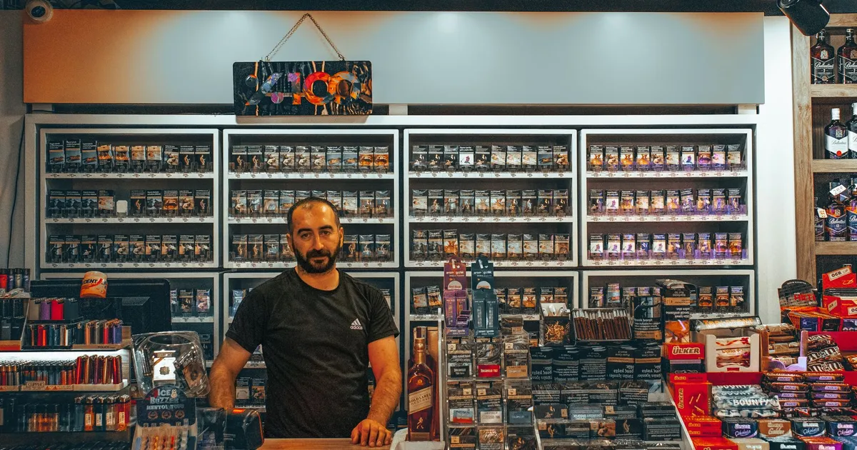 A merchant at a store counter with various products in Ankara, Türkiye.
