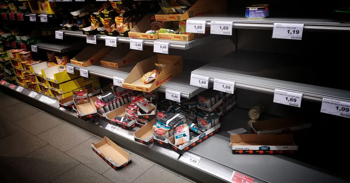 High angle of empty and full shelves in supermarket with price tags and cardboard boxes